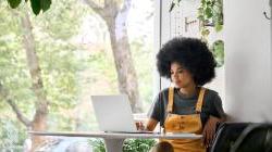 年轻快乐的非裔美国女人在她的笔记本电脑上