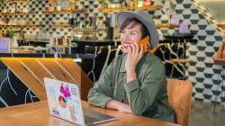 Juanny Romero, Owner of Mothership Coffee Roasters on phone with laptop in her cafe